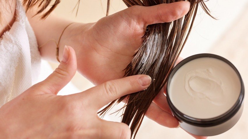 Mulher passando produto no cabelo