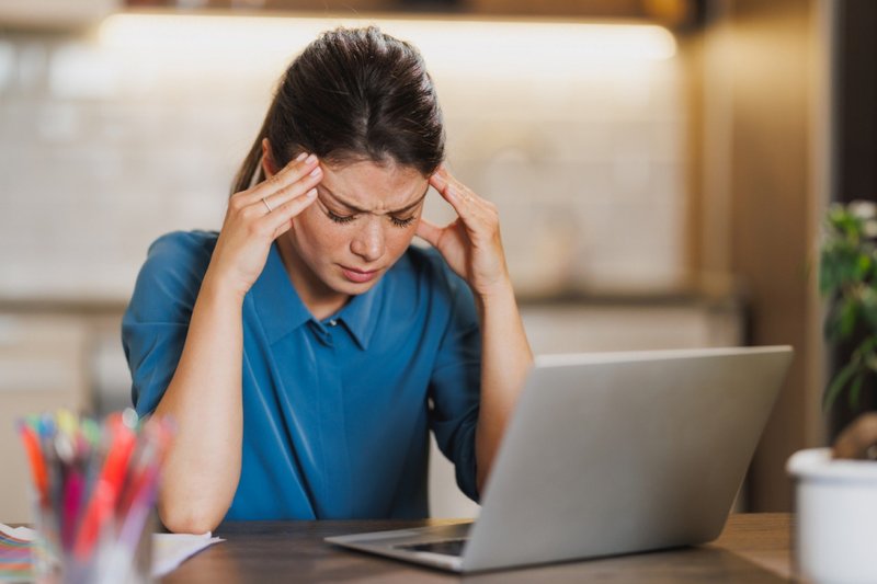 Empreendedora com aparência estressada enquanto trabalha no laptop em seu escritório em casa.