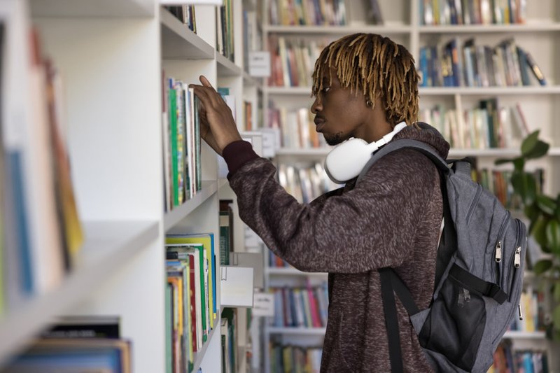 Homem procurando livros em prateleiras