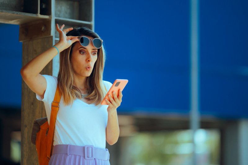 Imagem de uma mulher olhando para o celular com uma expressão de surpresa
