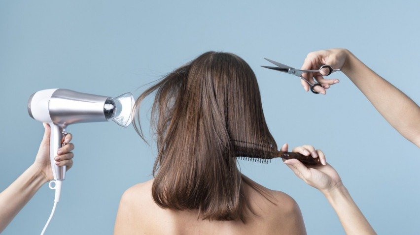 Imagem ilustrativa de figurina feminina de costas recebendo corte de cabelo.