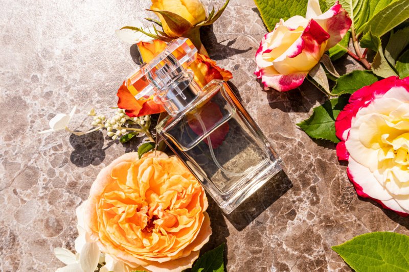 Um frasco de perfume apoiado em um ramo de flores.