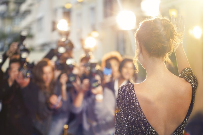 Imagem de celebridade acenando para fotógrafos paparazzi em evento