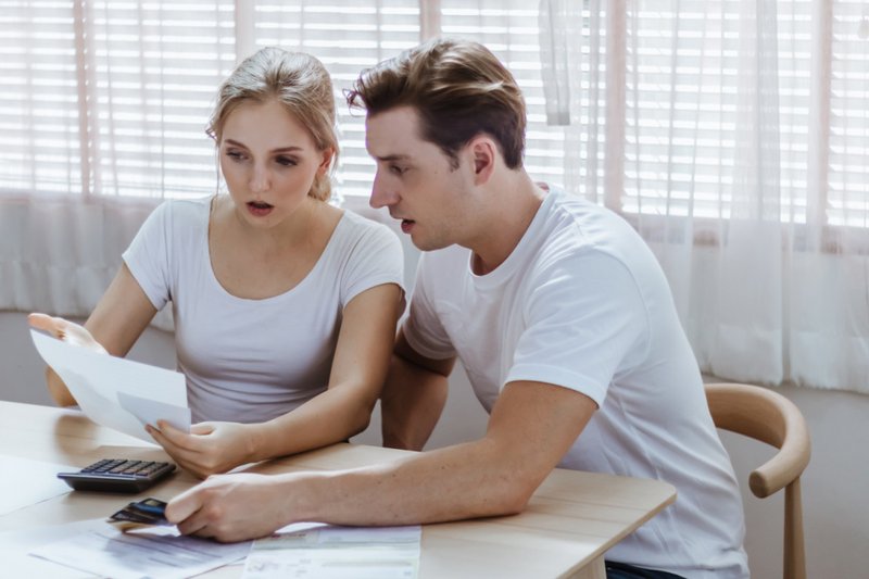 Imagem de um casal surpreso com dívidas