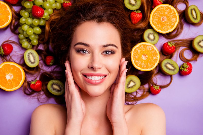 Mulher sorrindo rodeada de frutas