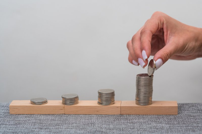 Imagem de conceito de um negócio em crescimento. Mão das mulheres para pôr moedas da pilha do dinheiro.