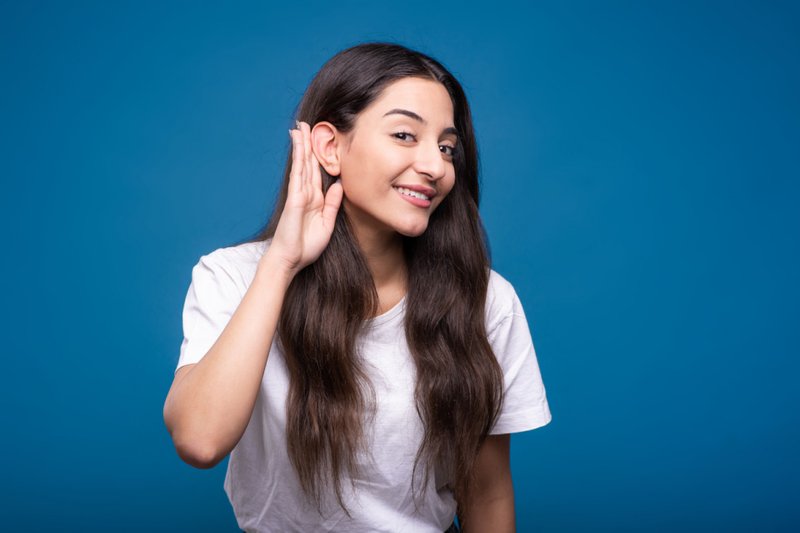Imagem de uma mulher com mão na orelha para escutar melhor