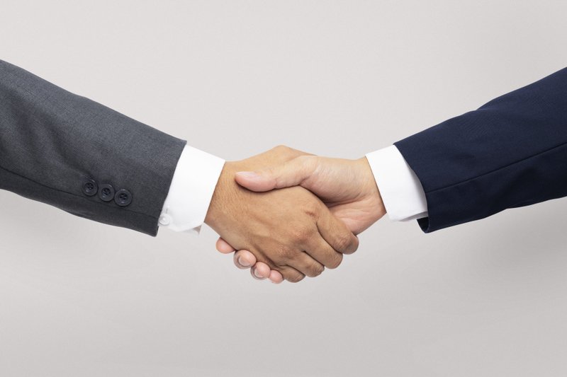 Imagem de duas pessoas apertando as mãos para fazer um acordo