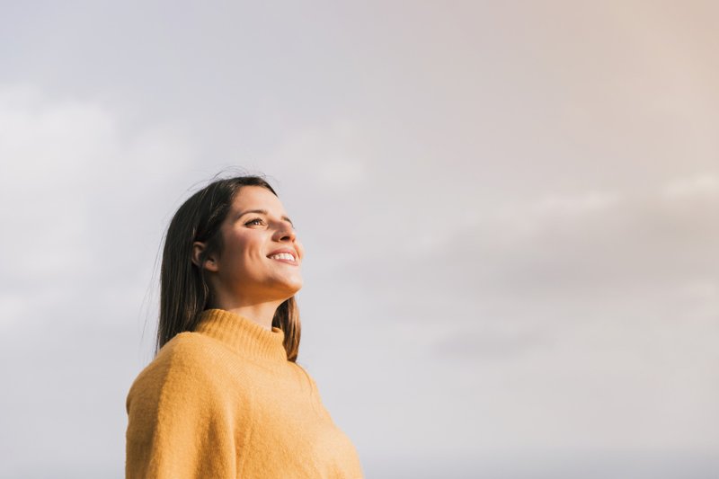 Imagem de uma mulher sorrindo para a natureza