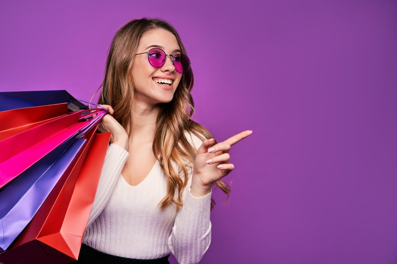Imagem de uma mulher sorridente com compras na mão