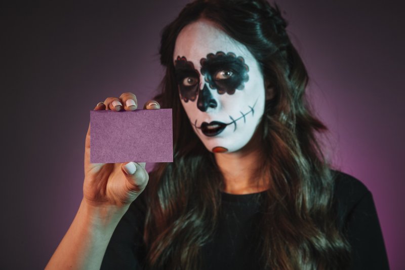 Menina com maquiagem de halloween segurando cartão de visita