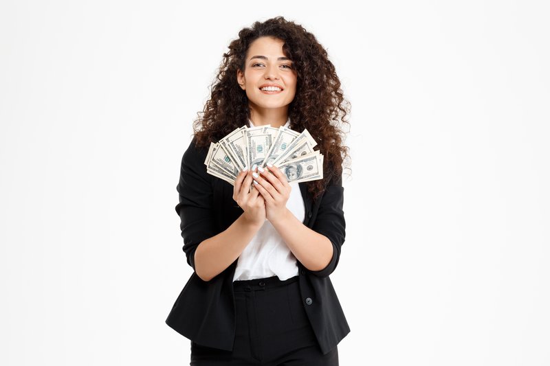 Picture of cheerful curly business girl holding money over white background