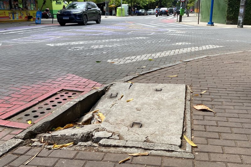 Tampa de concreto quebrada e faixa de pedestres apagada