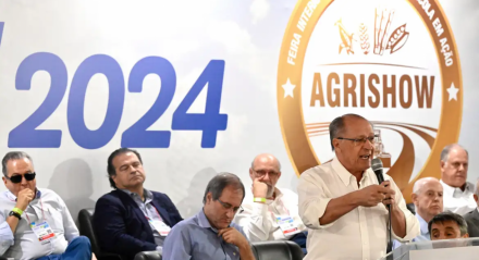 Vice-presidente Geraldo Alckmin no Agrishow 2024. Político fala ao microfone em palco com diversas pessoas sentadas