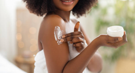 Imagem ilustrativa de mulher passando creme na pele.