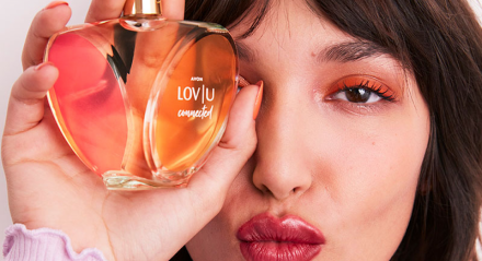 Mulher segurando o perfume LOV|U da Avon 
