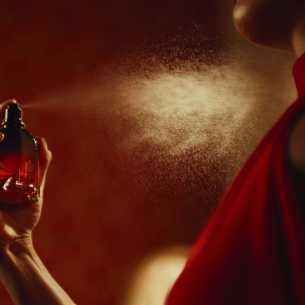 Imagem de mulher elegante passando o perfume "Floratta Red Passion", O Boticário.
