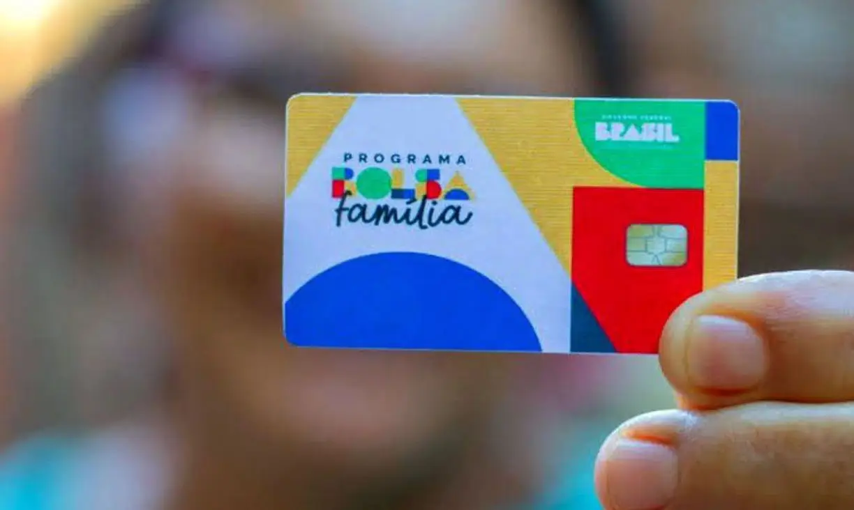 Imagem ilustrativa de mulher segurando o cartão do Bolsa Família