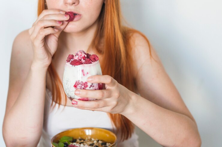 Imagem Ilustrativa de mulher comendo iogurte com frutas.