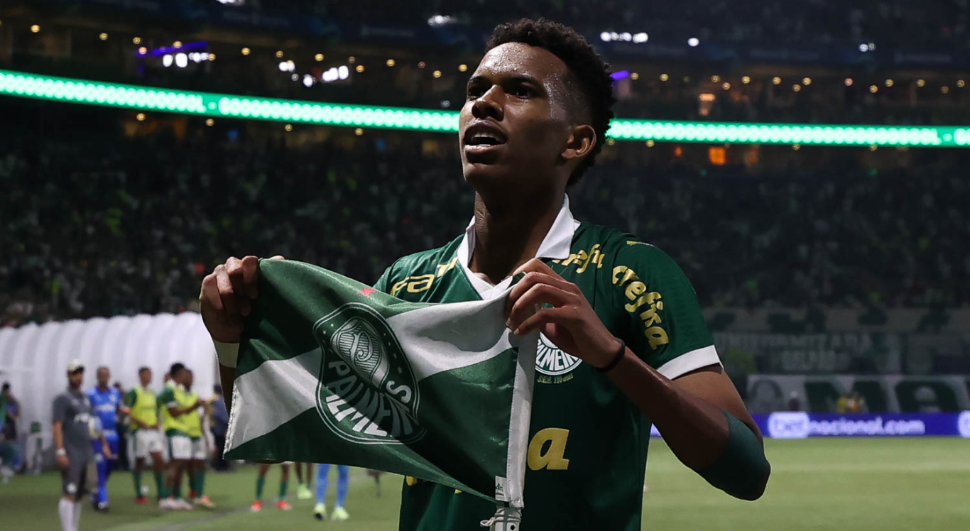 Imagem: Estevão segura a bandeira do Palmeiras e olha para a torcida
