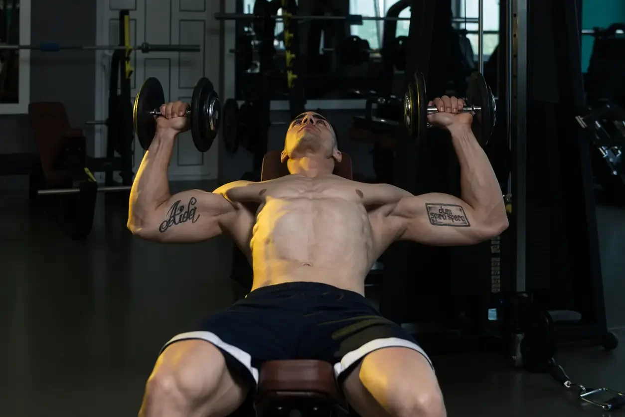 imagem ilustrativa de homem fazendo o exercício supino inclinado com halter na academia