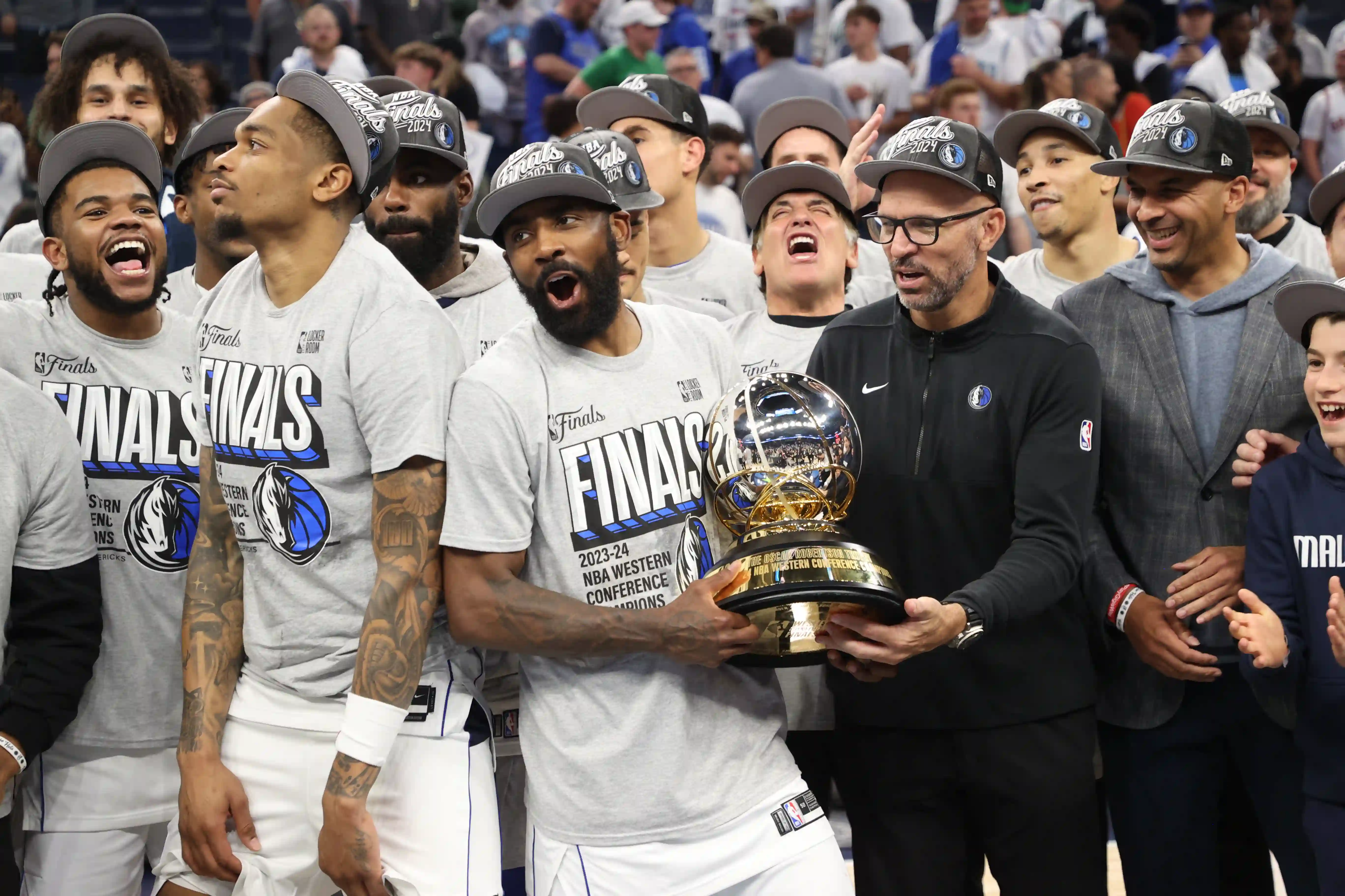 Imagem dos jogadores do Dallas Mavericks celebrando vitória das finais do Oeste com o troféu 
