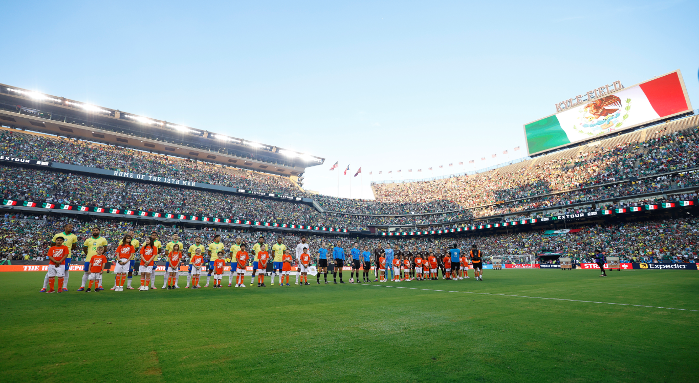Imagem dos jogadores do Brasil perfilados e vista ampla do Estádio Kyle Field