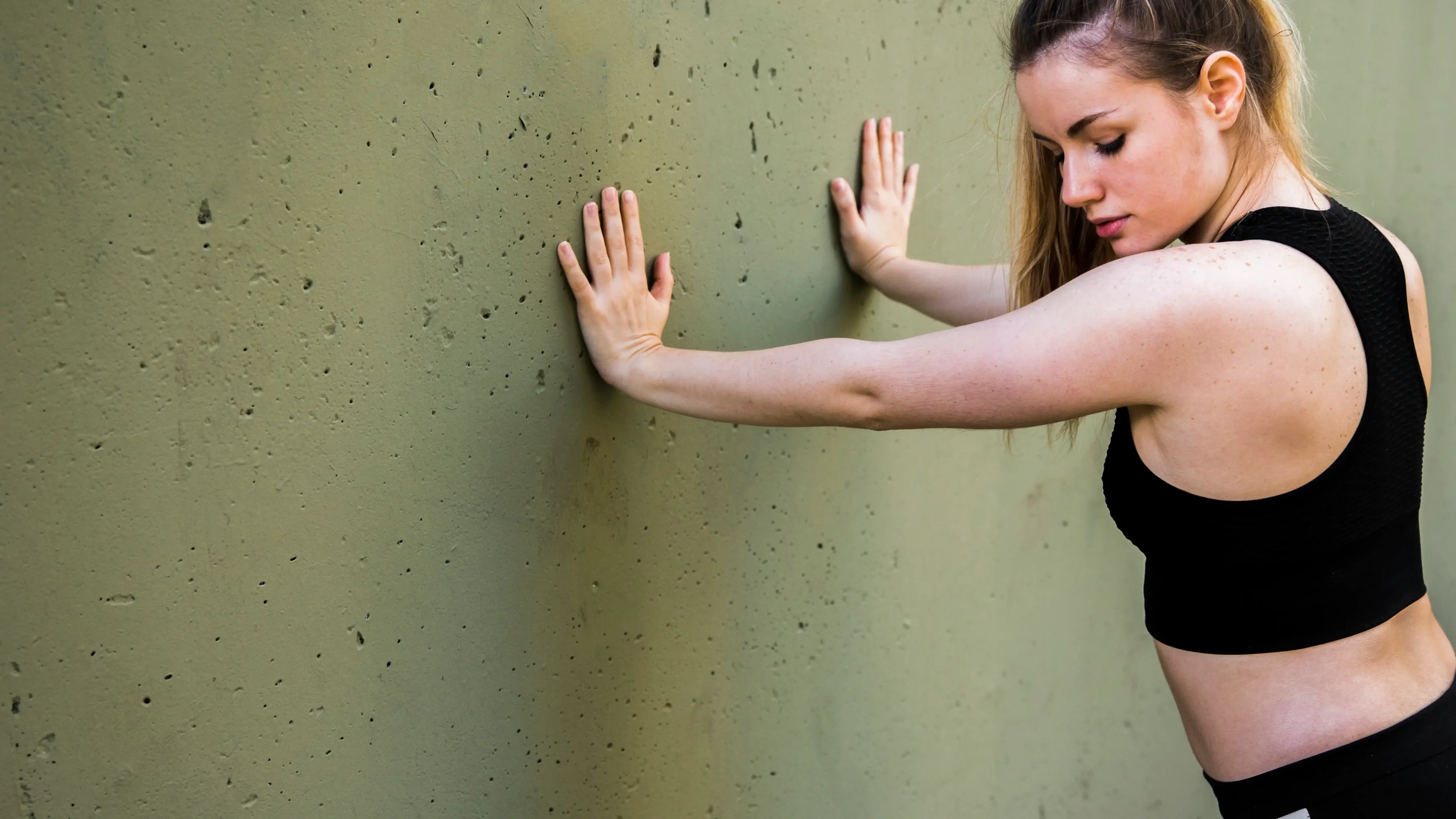 Mulher realizando exercícios de pilates na parede. 