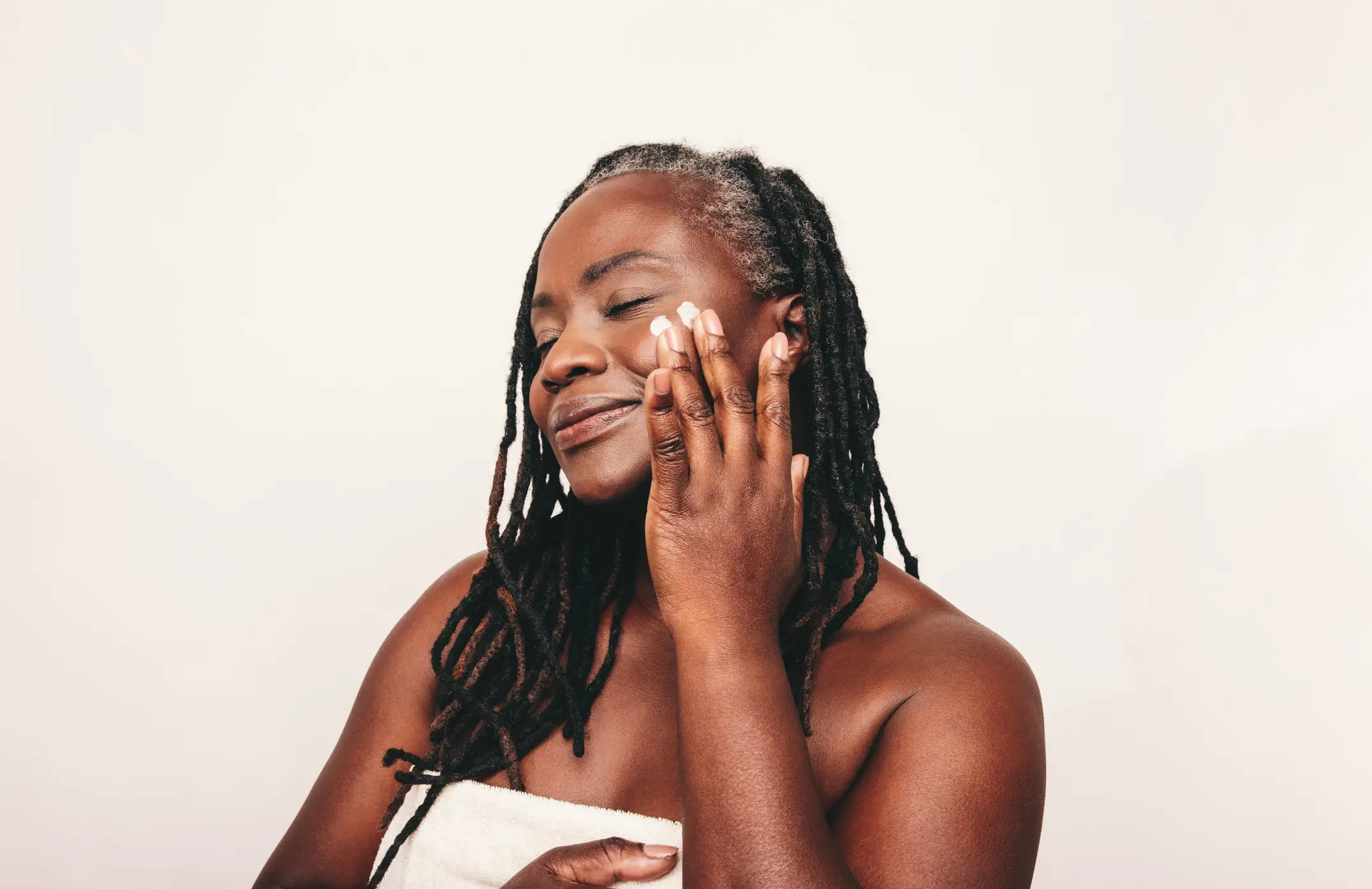 Imagem ilustrativa de mulher usando creme no rosto.