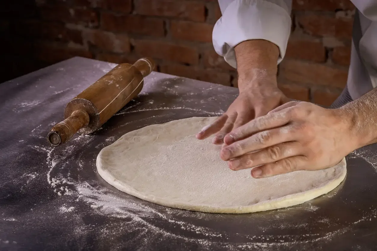 Imagem ilustrativa de pizzaiolo preparando massa de pizza