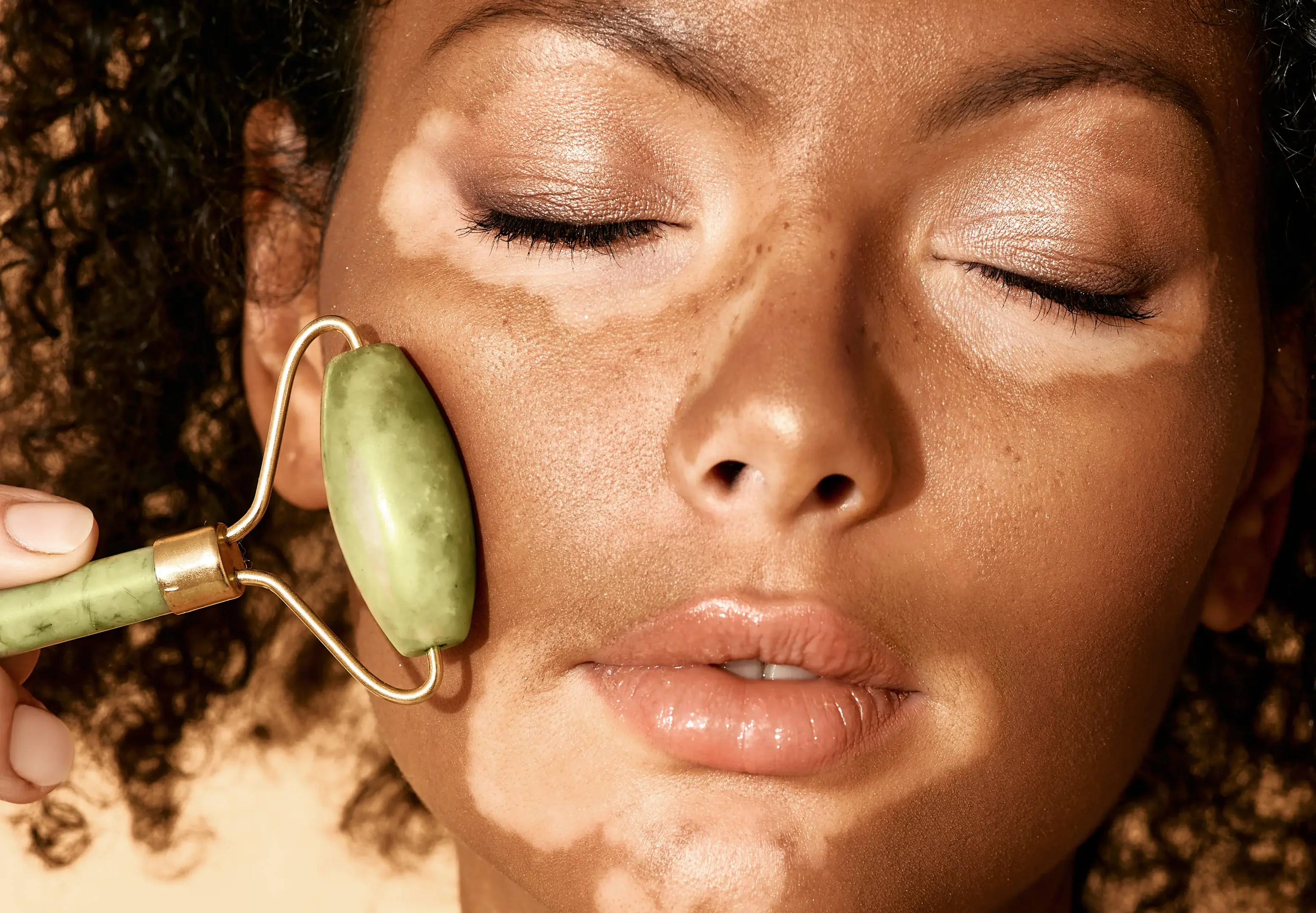 Imagem ilustrativa de mulher negra com vitiligo usando o massageador facial
