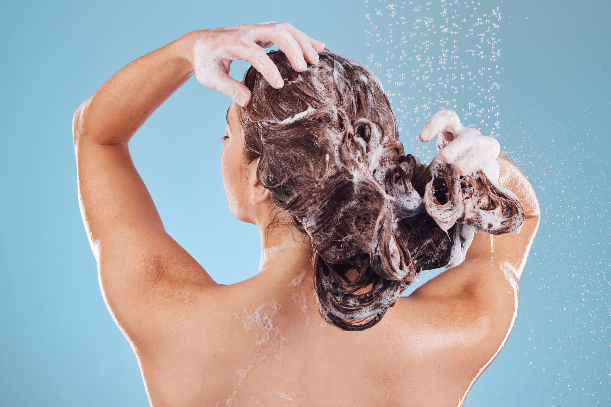 Modelo lavando o cabelo com shampoo.