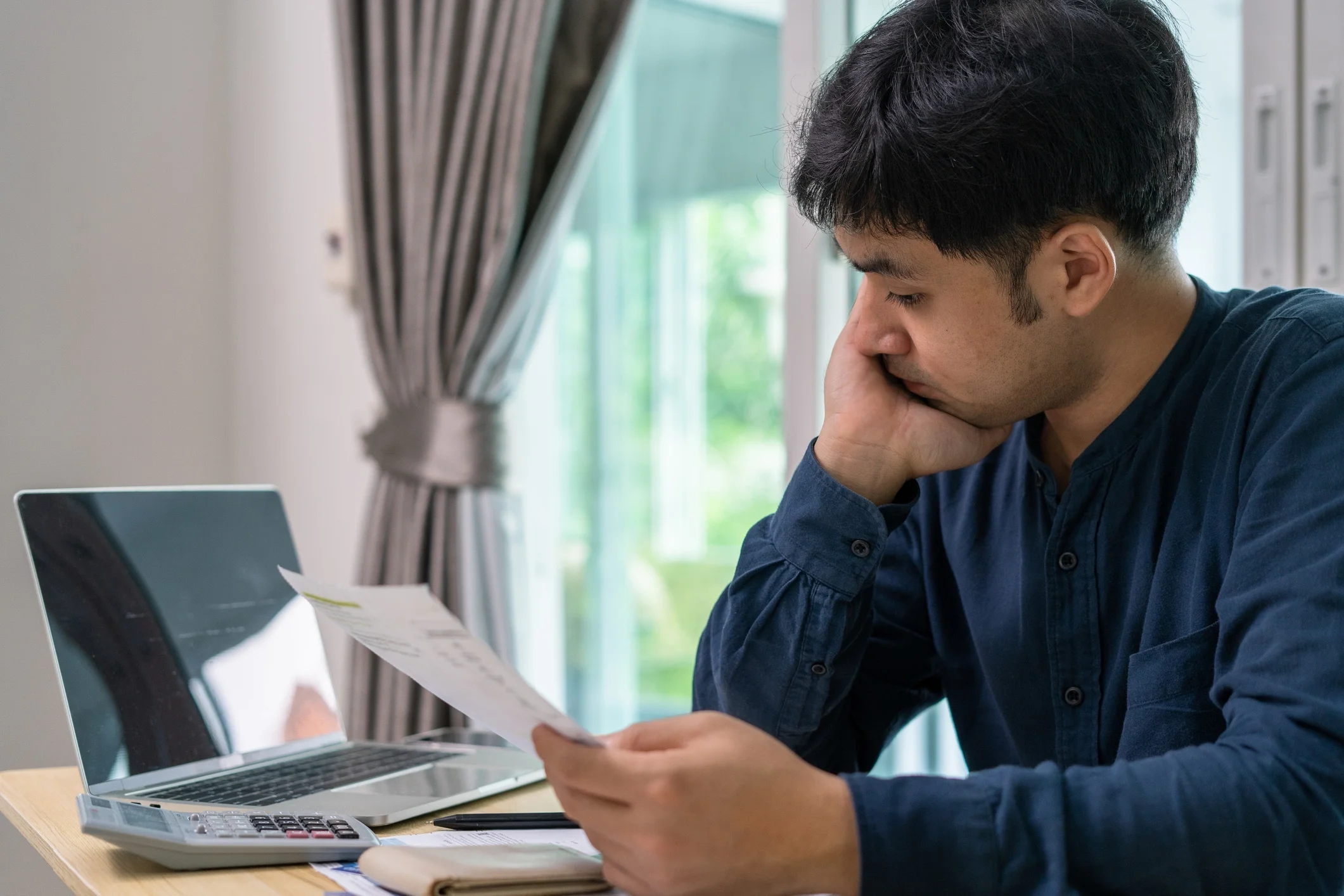 Homem estressado com muitas dívidas de cartão de crédito e contas na mesa. 