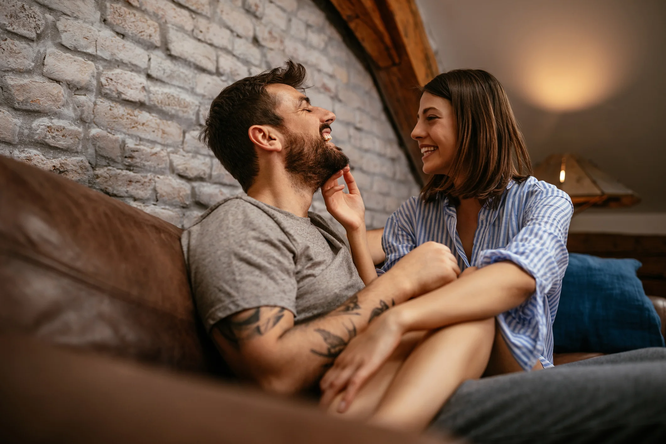 Casal em clima de romance sentados no sofá.