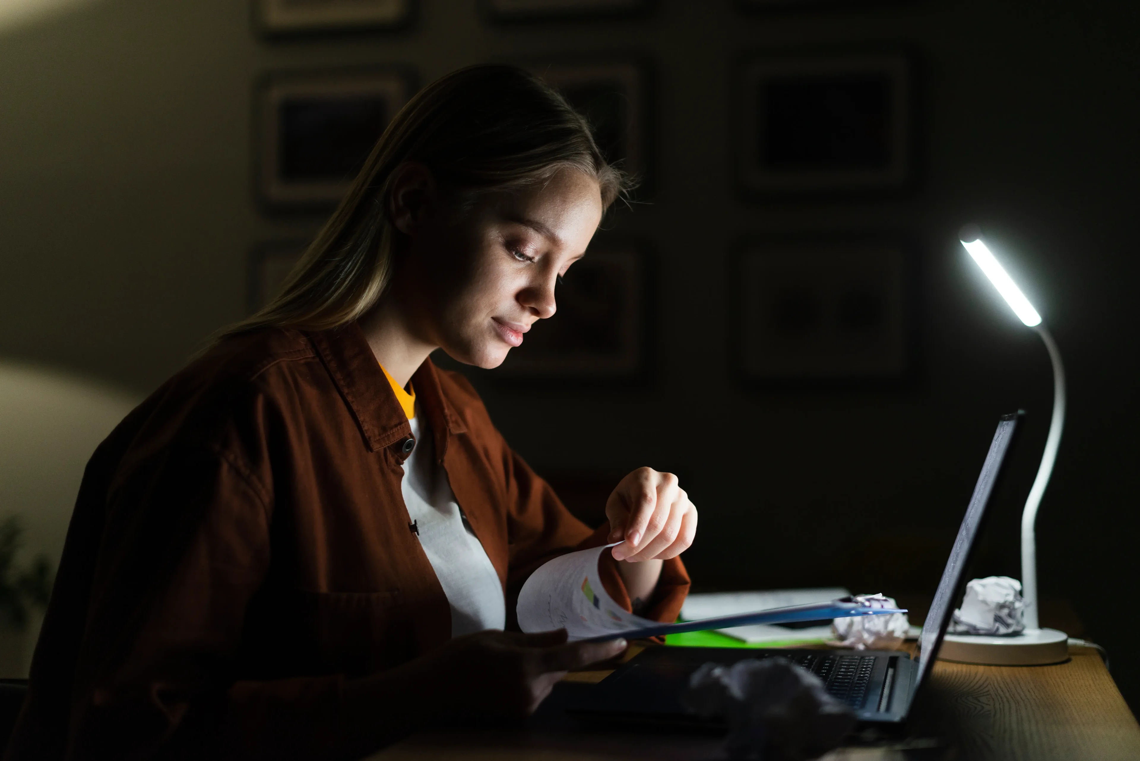 Imagem ilustrativa: mulher estudando à noite com luminária ligada. 