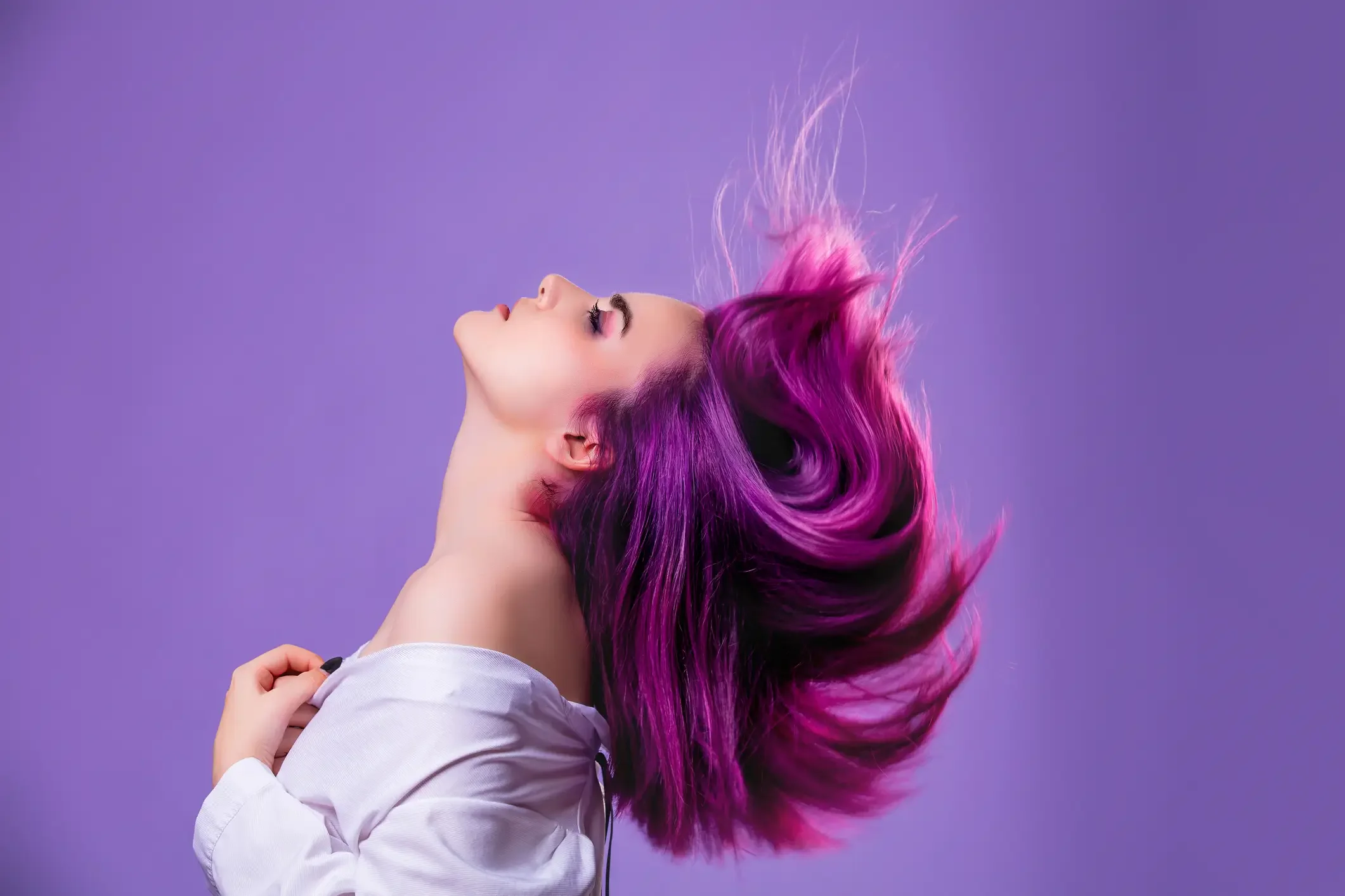 Imagem ilustrativa de mulher com cabelo tingido roxo no fundo violeta