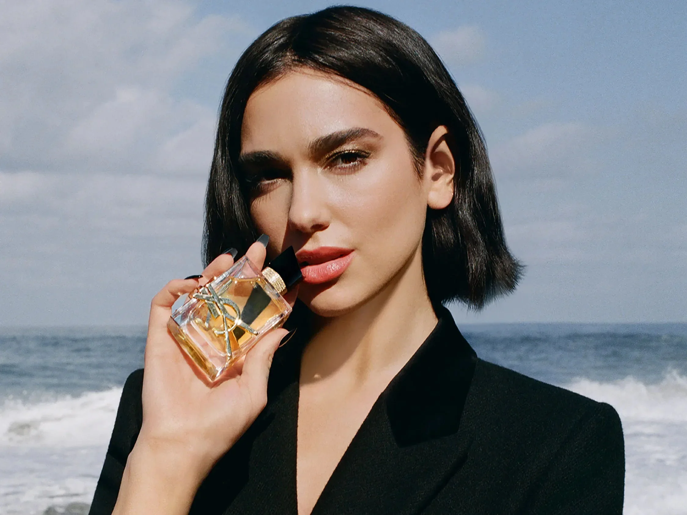 Dua Lipa segurando o perfume Libre Intense