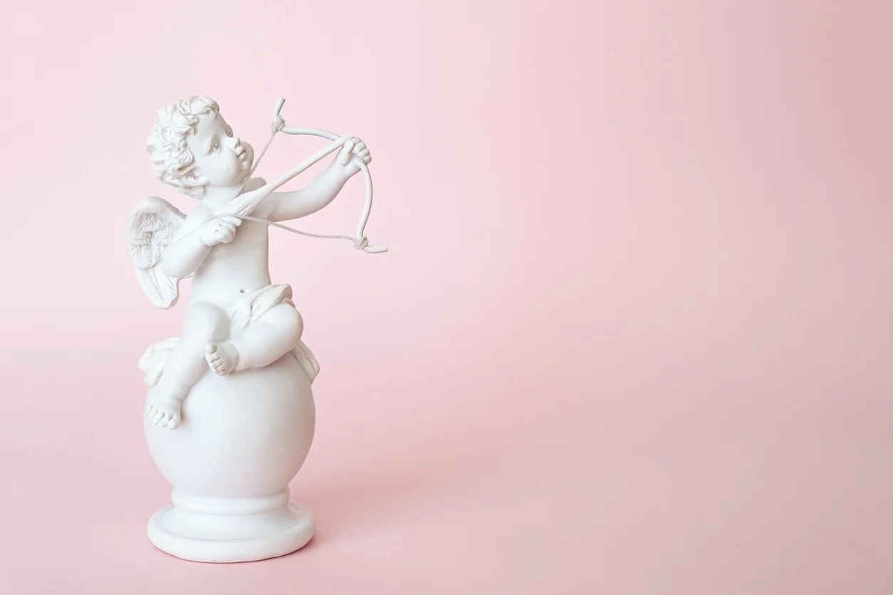 Estatueta de um cupido anjo com um arco em um fundo rosa