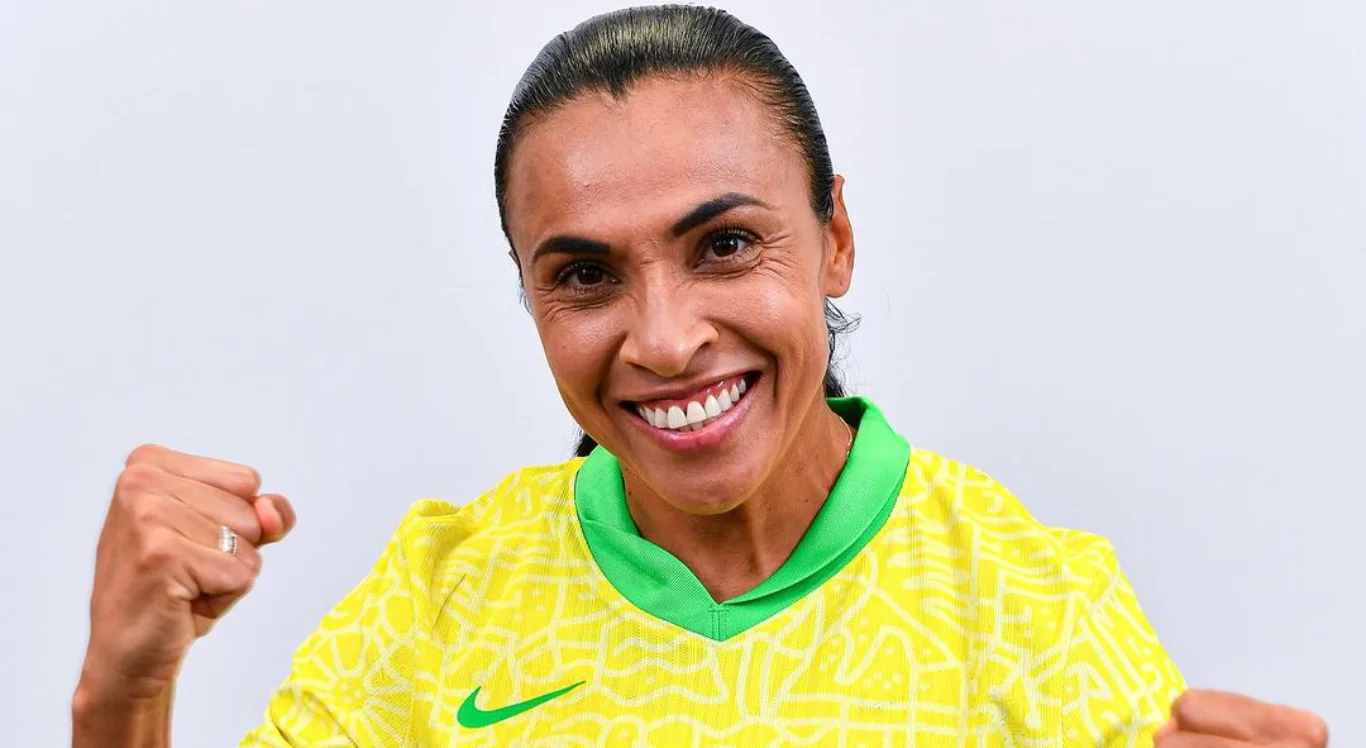 Marta pousa para foto sorrindo e com os punhos erguidos