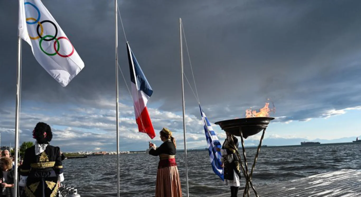 Imagem da bandeira francesa, grega e a pira olímpica