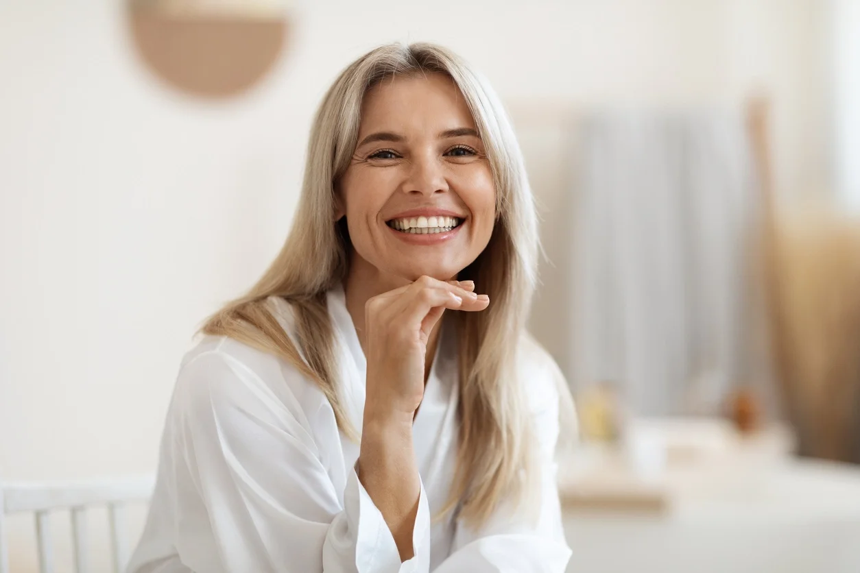 Mulher loira feliz que posa no banheiro branco em casa