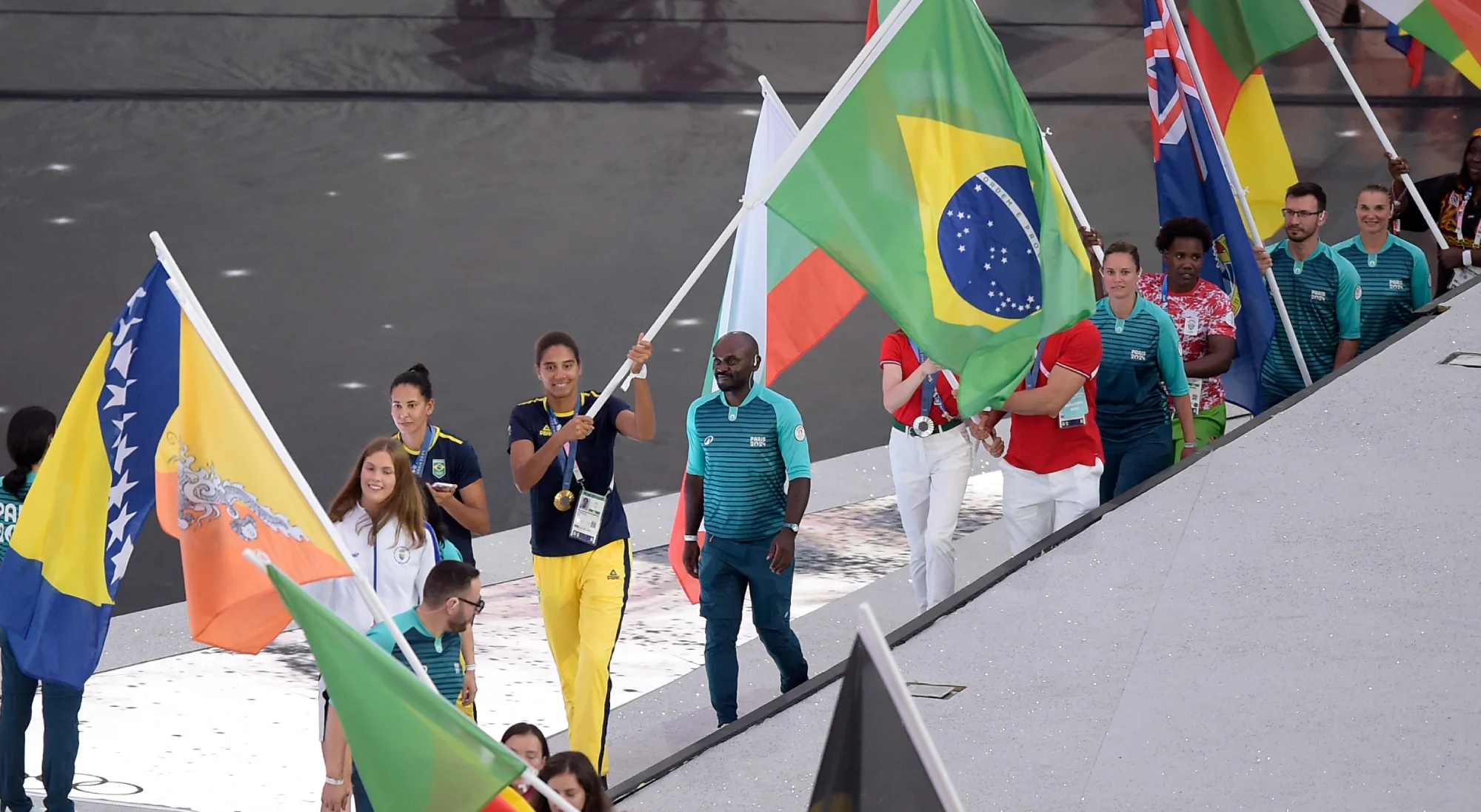 As medalhistas de ouro olímpicas no vôlei de praia, Duda e Ana Patricia, conduzem a bandeira do Brasil na entrada para a Cerimonia de Encerramento dos Jogos Olímpicos Paris 2024