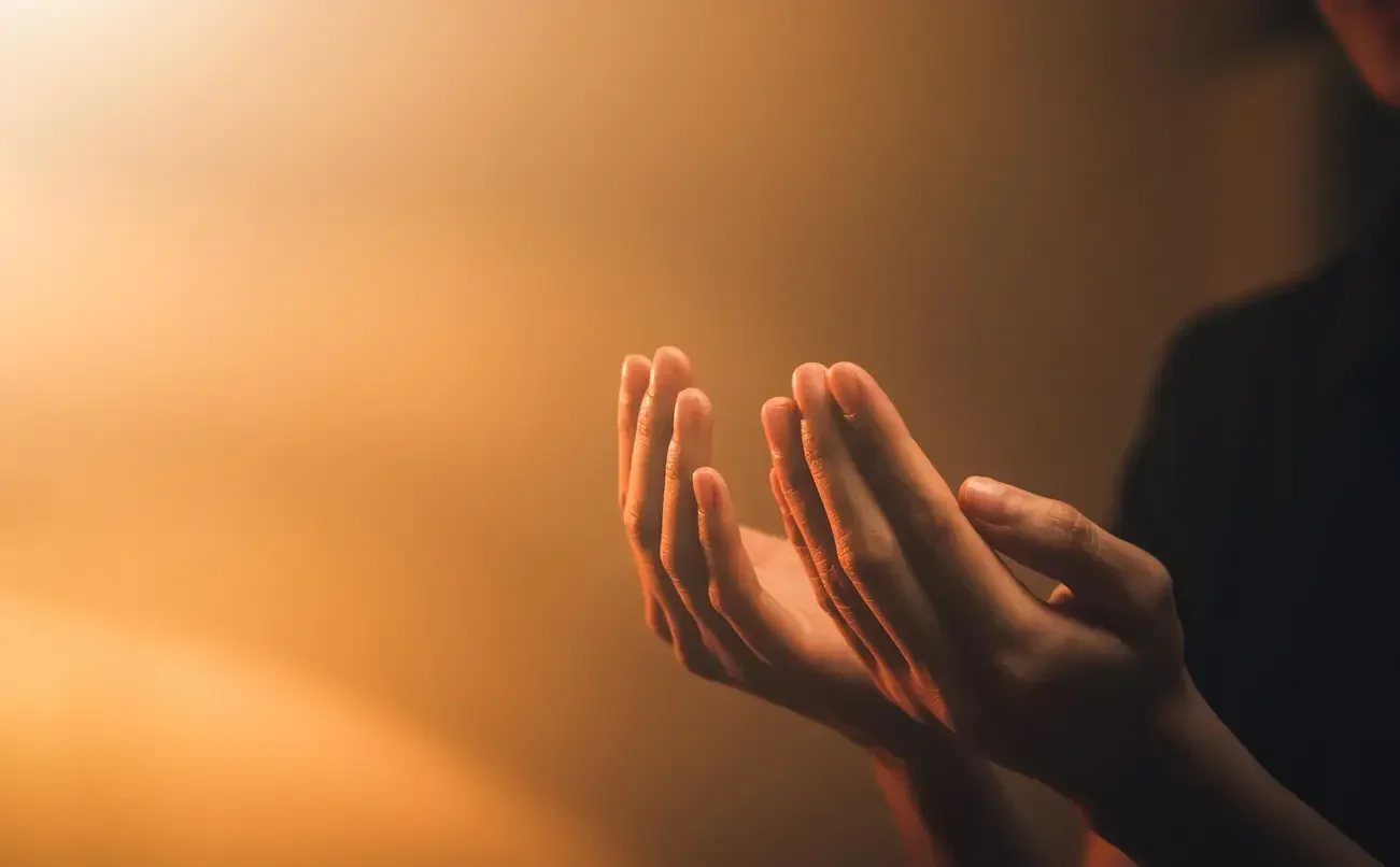 Imagem de uma pessoa levantando as mãos em símbolo de oração