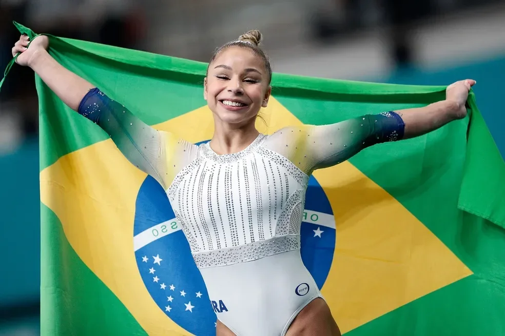 Imagem ilustra a atleta Flávia Saraiva com uma bandeira do Brasil